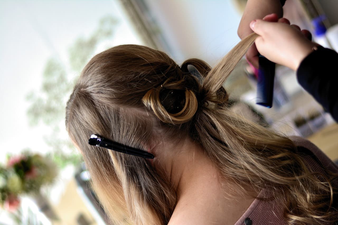 A stylist pinning and curling long, honey-toned hair at the back